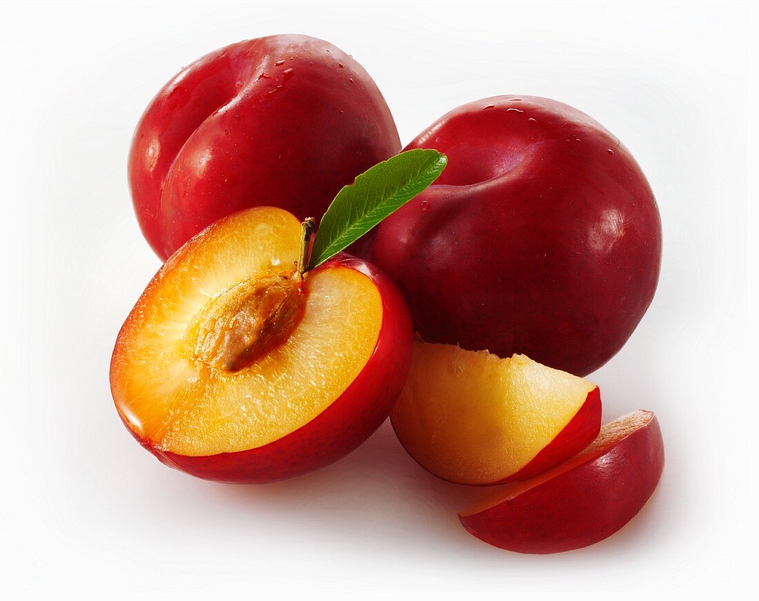 Whole red plums, halved plums and plum slices