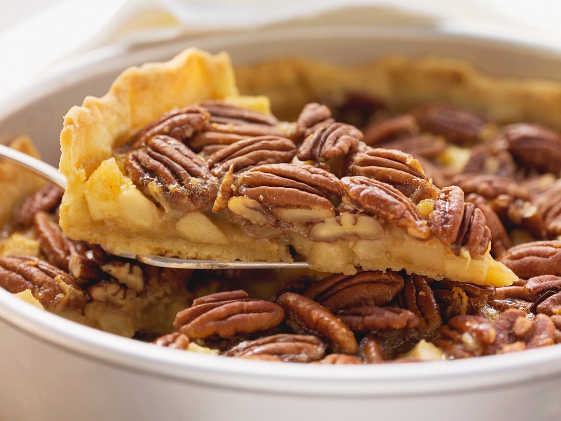 Pecan and apple pie in pie dish, one piece on cake slice