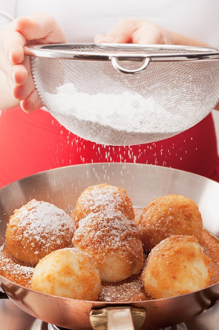 Dusting apricot dumplings with icing sugar