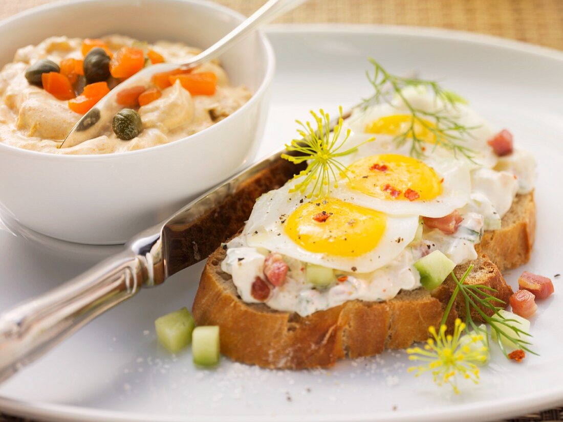 Open-faced sandwich of sour cream and vegetable spread with quail's eggs and small bowl of Liptauer (spicy cheese spread)