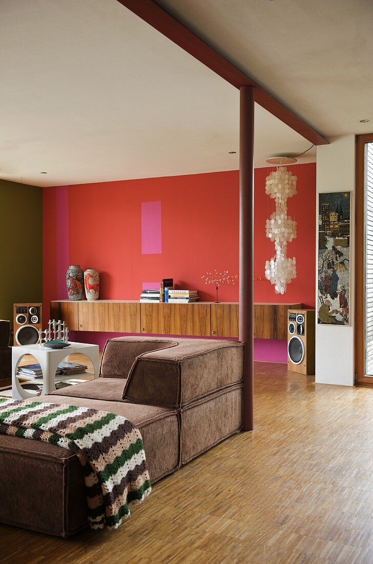 Retro living space with brown sofa and sideboard against red-painted wall