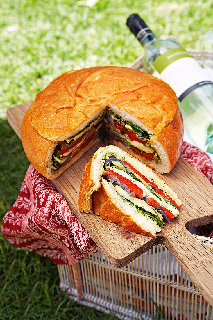 Gefülltes Brot fürs Picknick auf Holzbrett im Freien