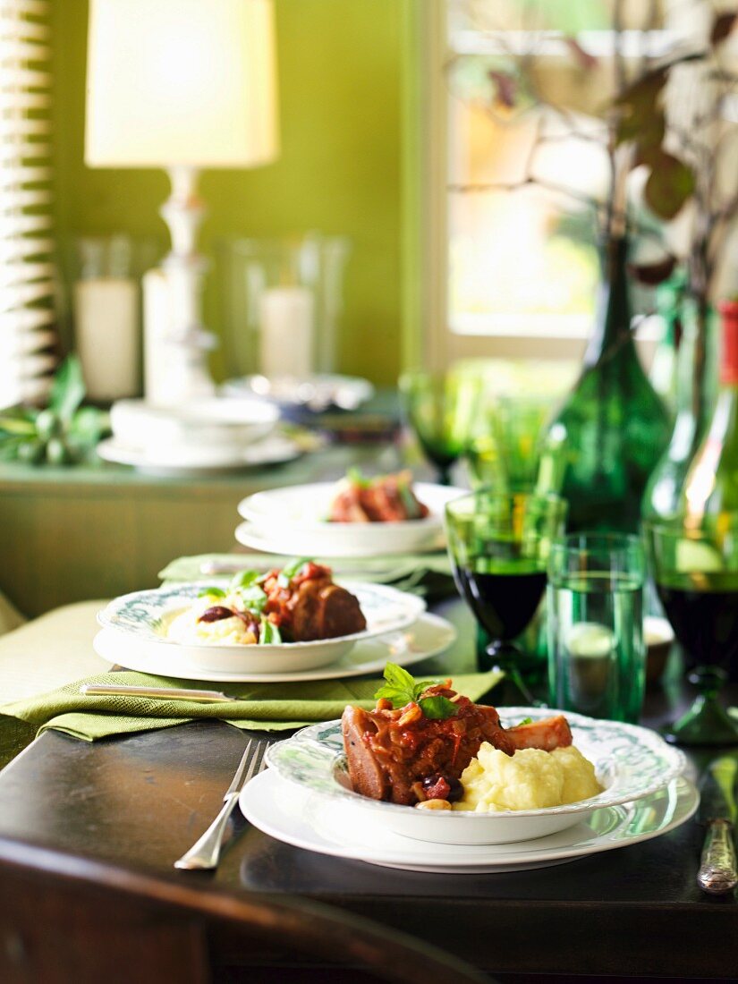 A table laid with plates of knuckle of veal on a bed of mashed potatoes