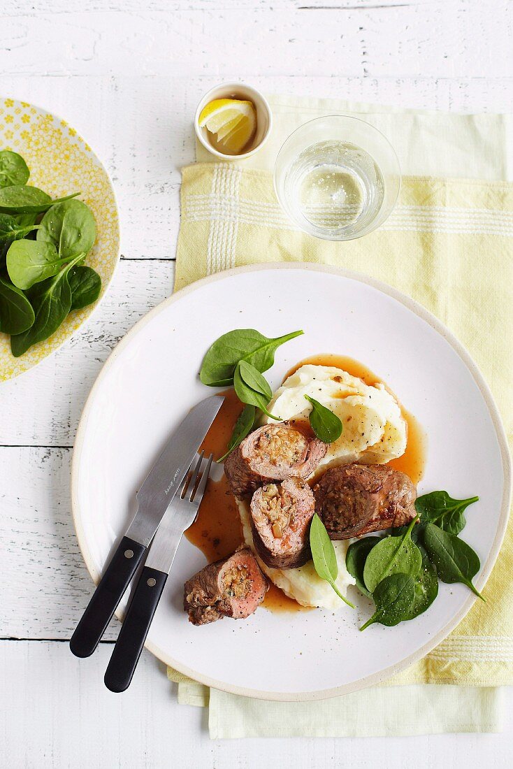 Beef roulade filled with olives and served with mashed potatoes and baby spinach