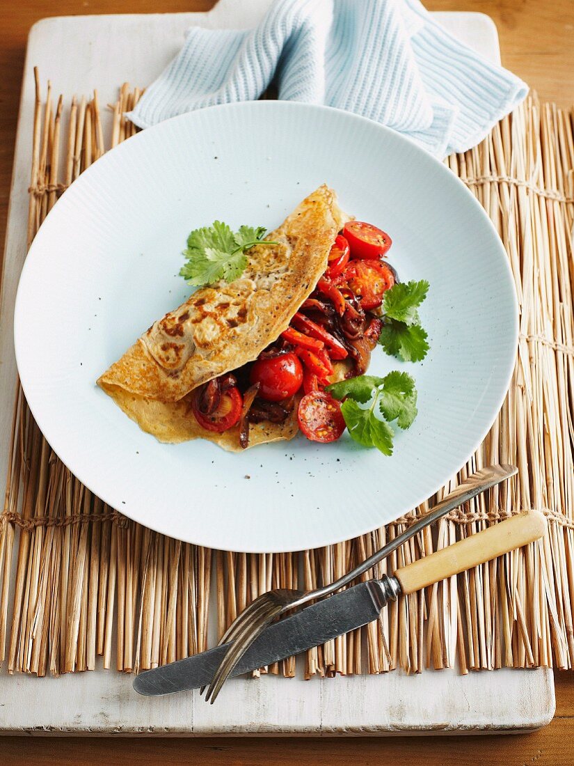 A pancake with cherry tomatoes and peppers