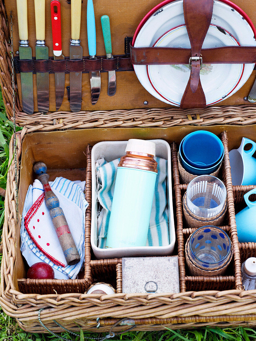 A picnic basket filled with crockery, glasses and cutlery