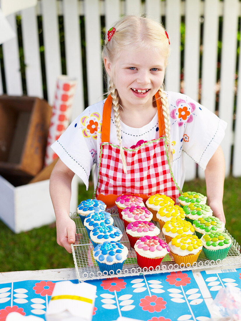 Mädchen bietet Cupcakes beim Schulfest an