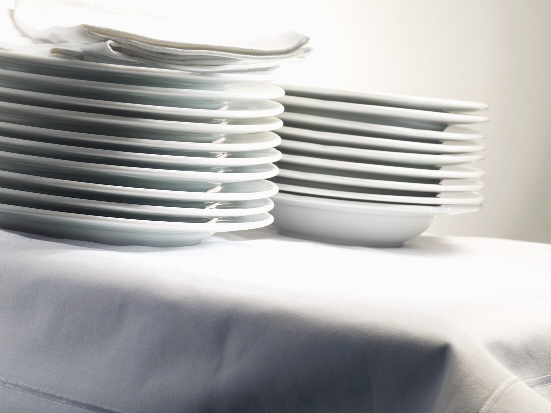 Stacked porcelain plates and linen napkins on table