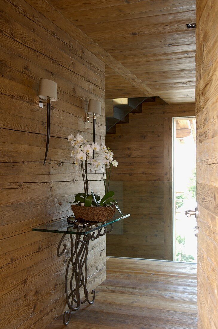 Orchid on ornate console table in hallway of wooden house