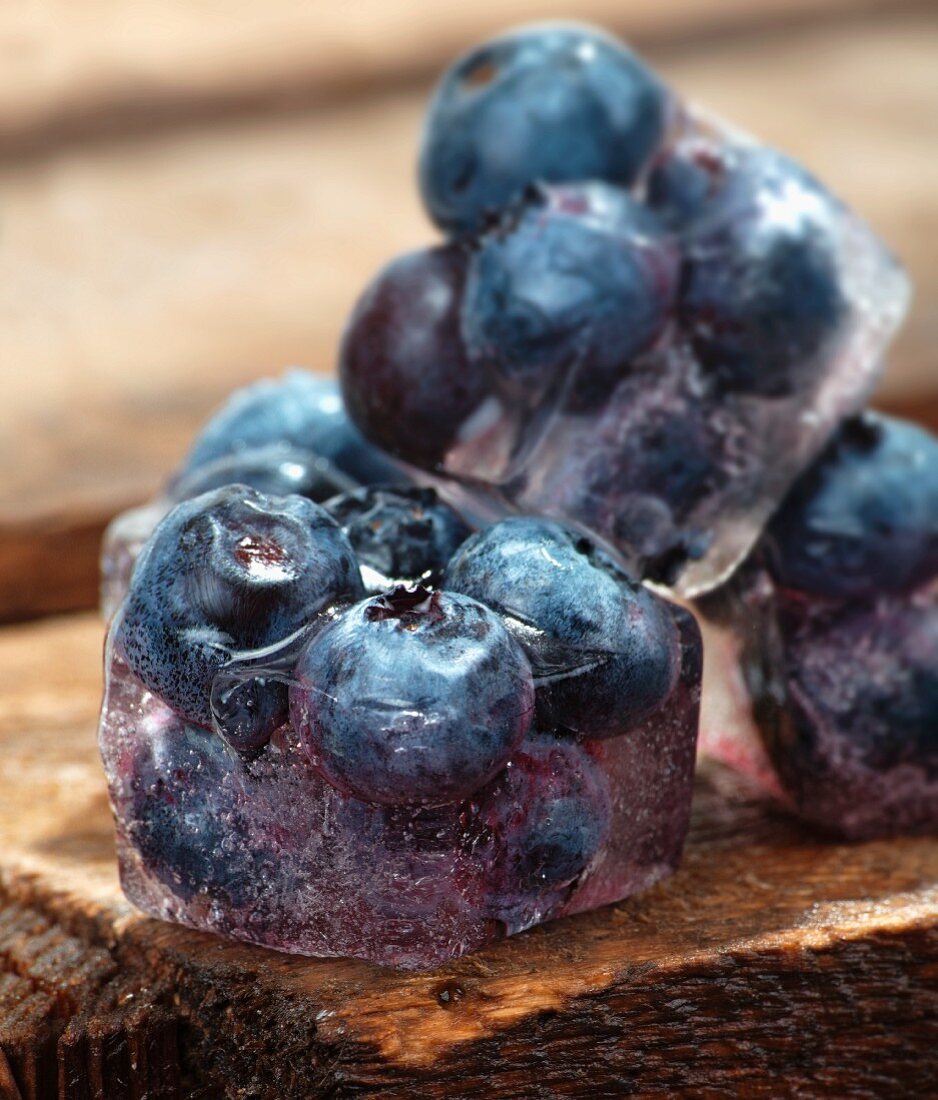 Ice cubes with blueberries on a wooden table