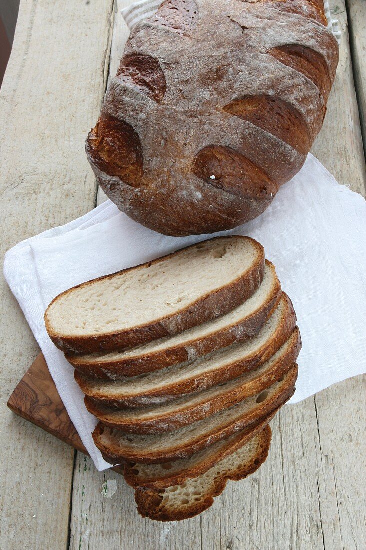 Rustic bread baked in a wood-fired oven, whole loaf and sliced