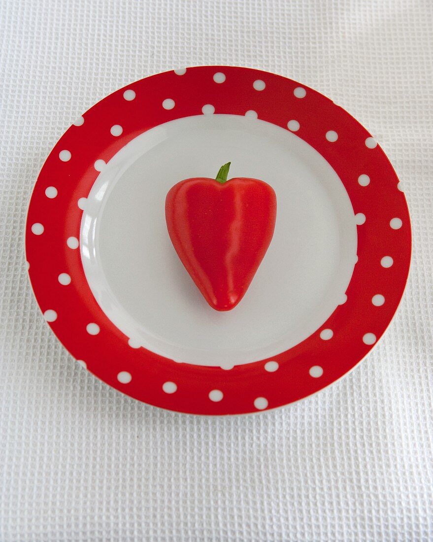 Herzförmige, rote Chilischote auf Teller