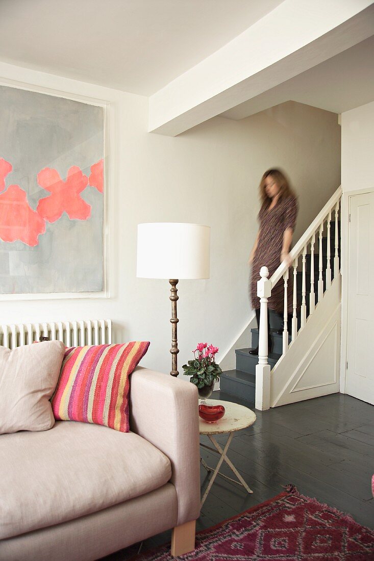 Lady going down stairs in a renovated country home with contrasting contemporary and antique furnishing