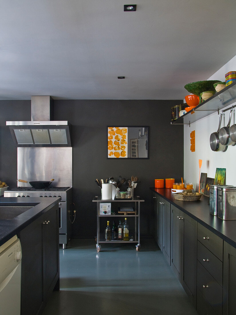 Grey kitchen counter and island in front of stainless steel cooker with extractor hood against grey-painted wall