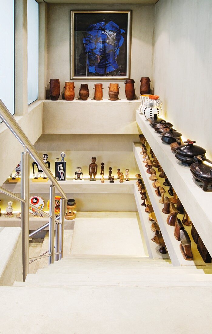A collection of ceramic containers and figures on built-in shelves in a stairwell