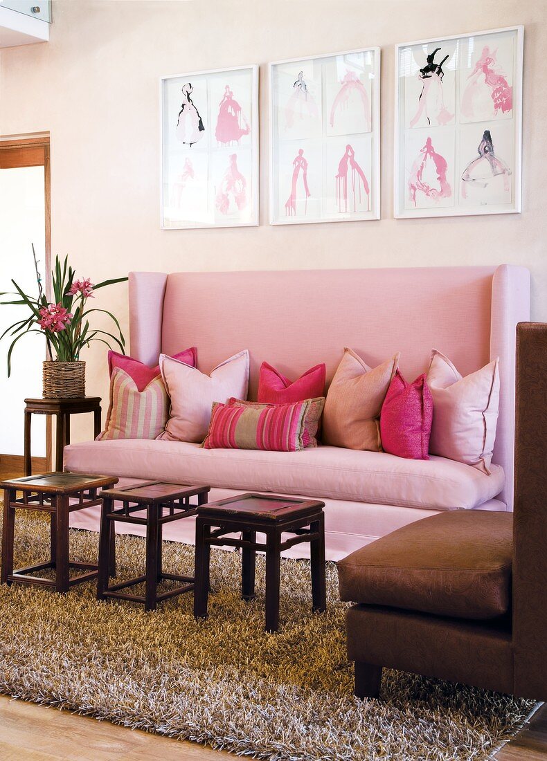 Rustic side tables in front of lilac, high-backed sofa with scatter cushions