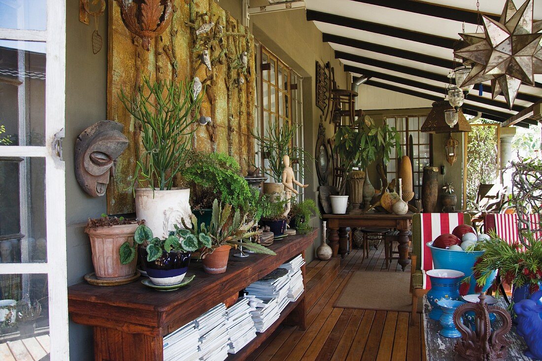 Blooming veranda with a solid wood sideboard, a collection of blue vases and plants in terra cotta pots
