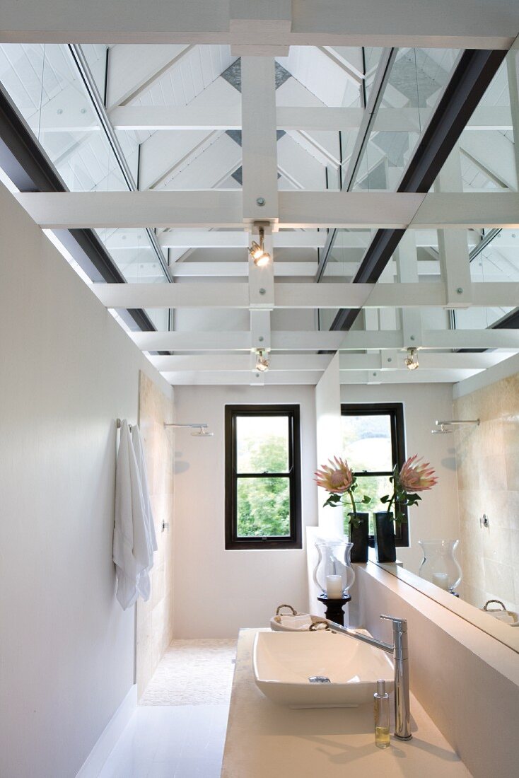 Mirror effects in narrow bathroom with modern washstand and shower area below exposed roof structure