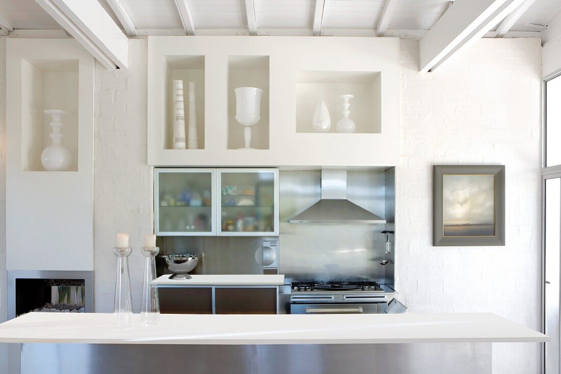 Table in front of a brick wall with openings for shelves and a mini kitchen counter