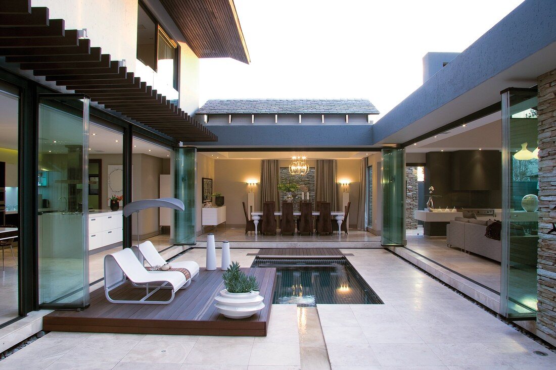 A U-shaped living area - opening into a courtyard with a pond and loungers on a wooden deck