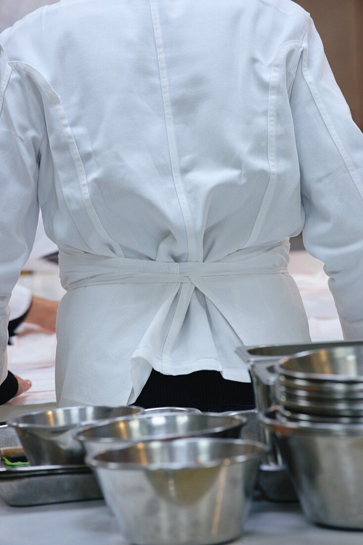 A chef and stainless steel bowls in a commercial kitchen