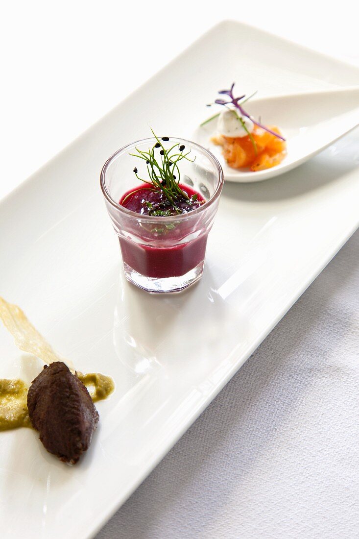 An appetizer platter with olive paste, beetroot soup and smoked salmon