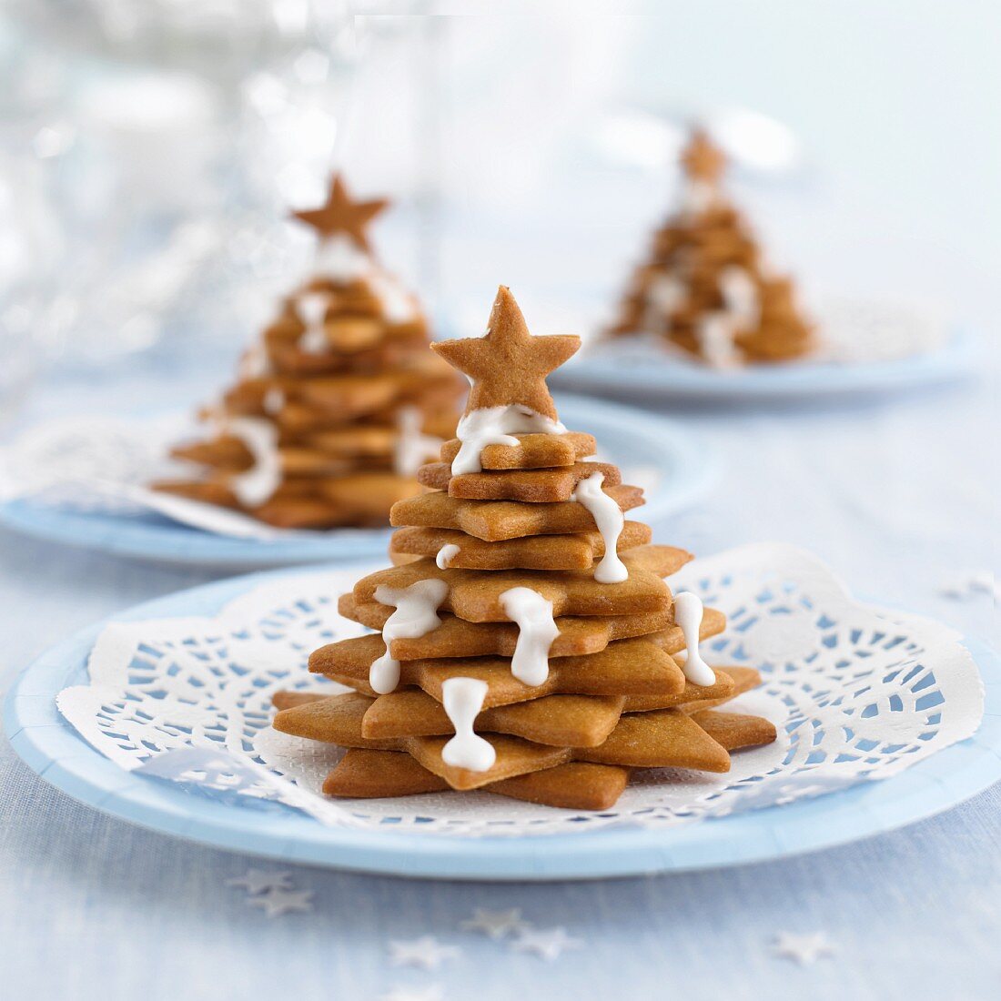 Biscuits stacked into Christmas trees decorated with icing sugar