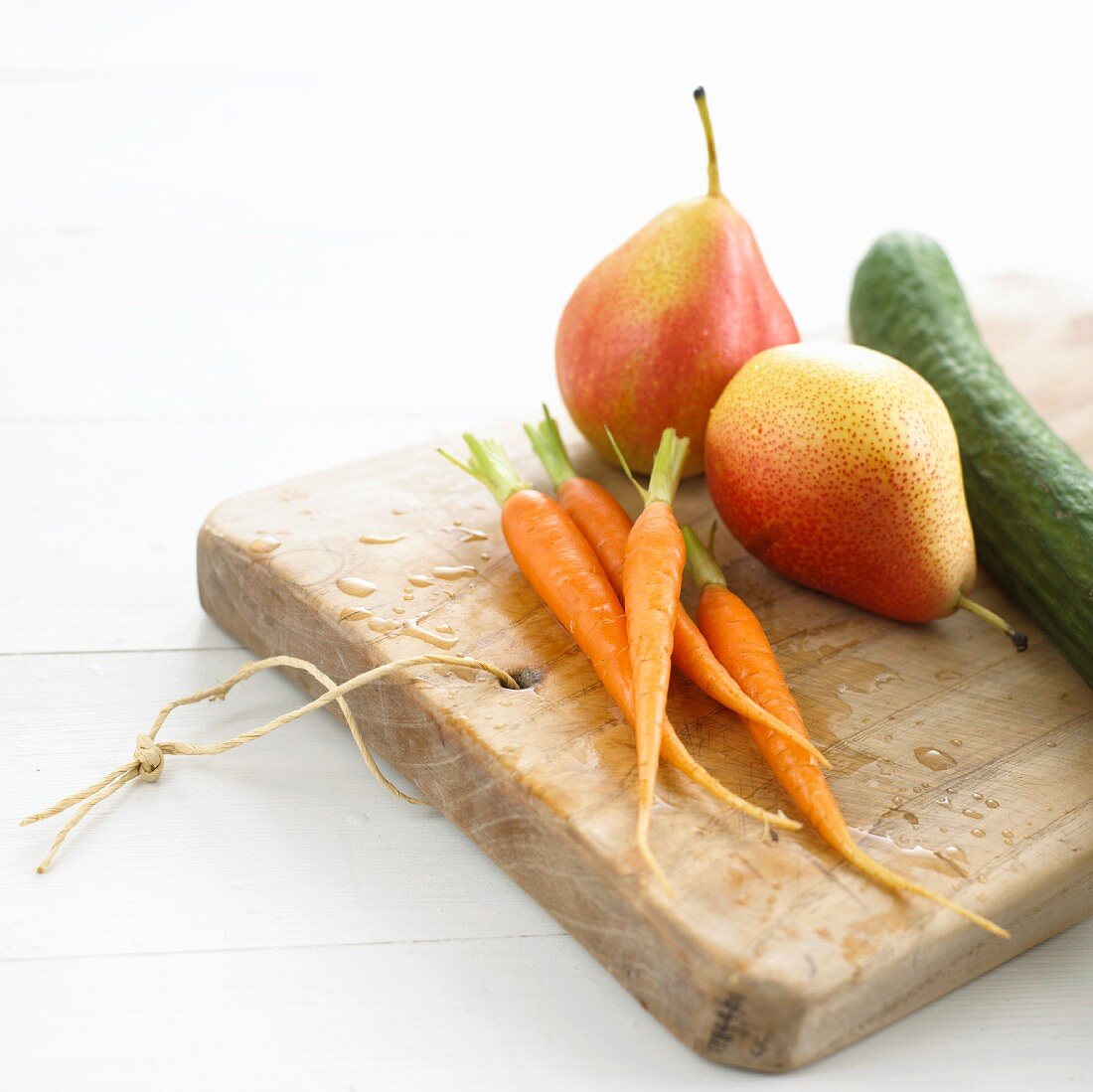 Carrots, pears and a cucumber on a chopping board