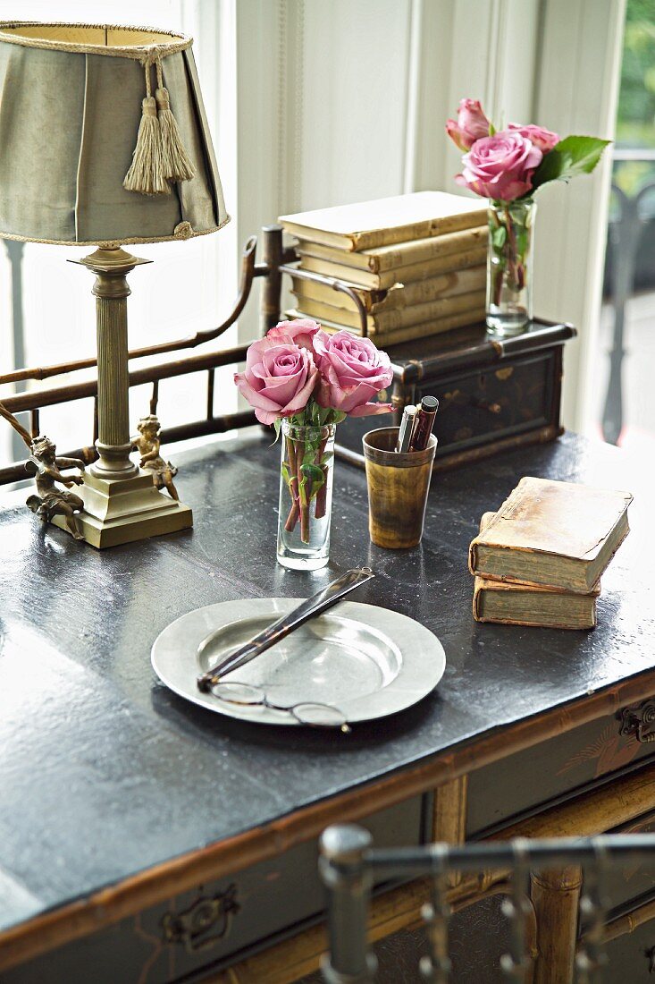 Breakfast plate and antiquarian books in front of posy of roses on desk