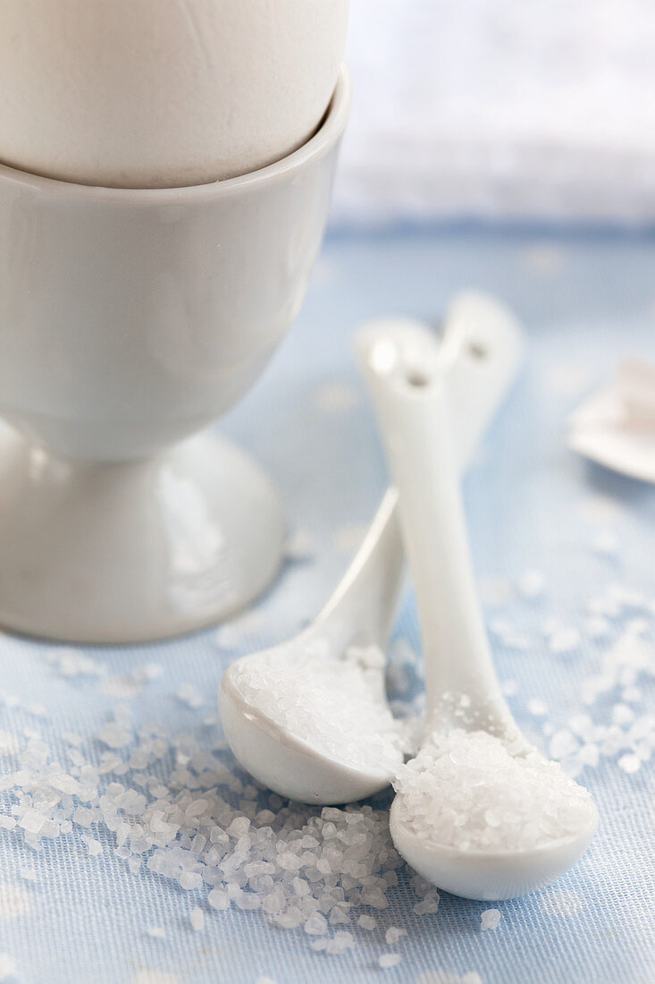Sea salt on porcelain spoons next to an egg cup