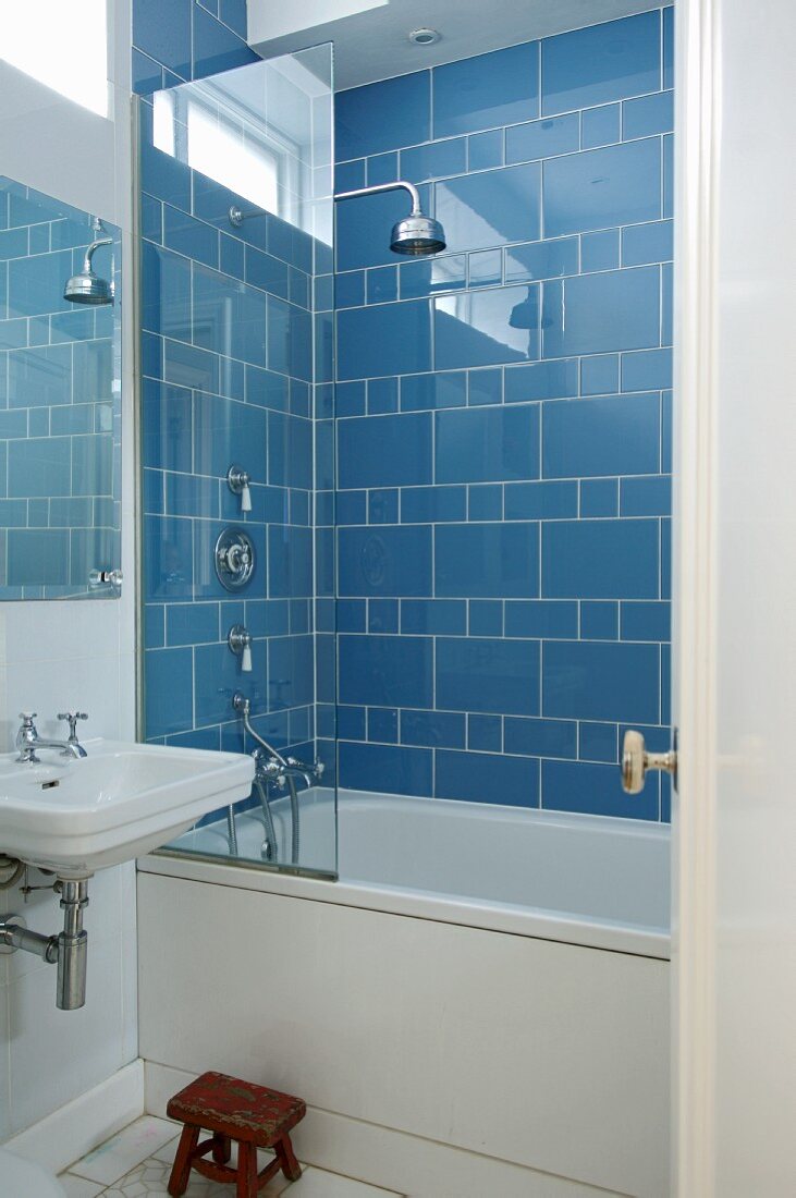 Badezimmerecke mit Badewanne und Kopfbrause vor blauen Wandfliesen