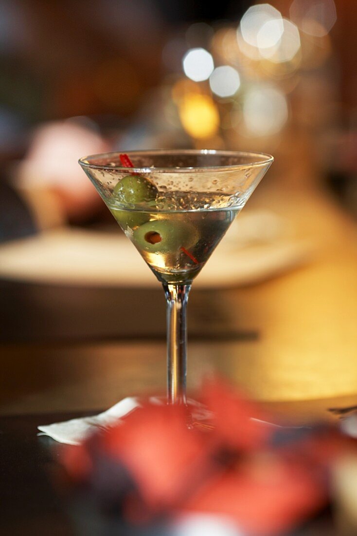 Ein halb ausgetrunkener Martini mit grünen Oliven