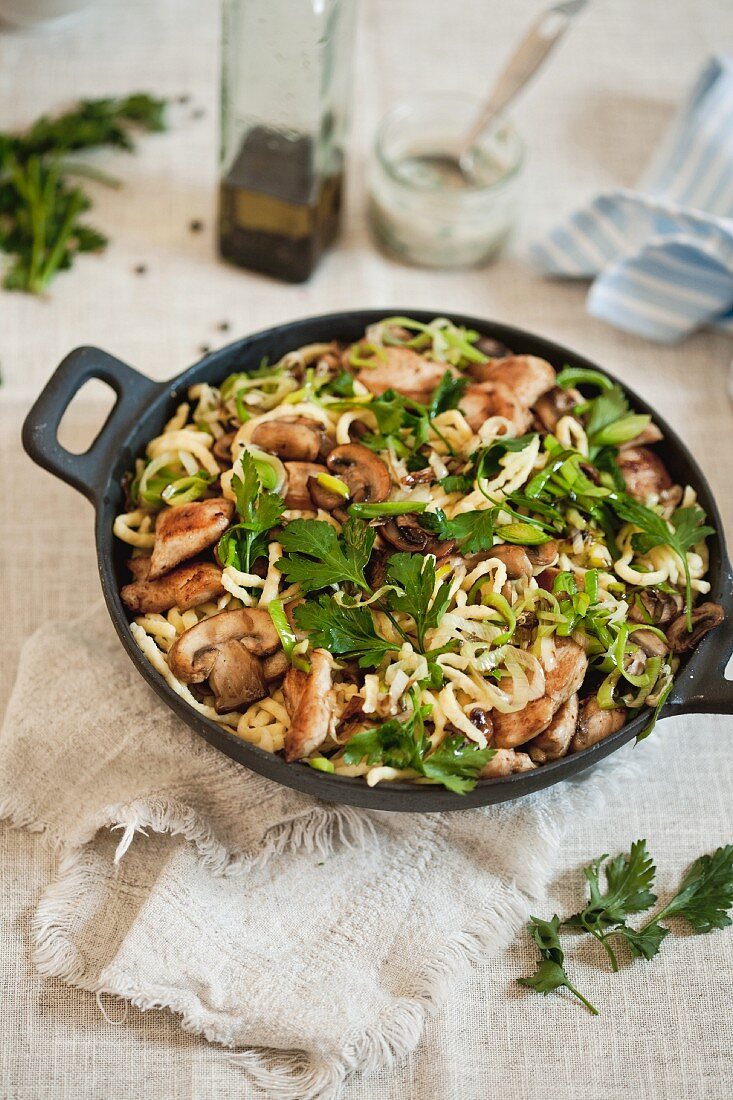 Spätzle mit Champignons und gebratenem Hähnchenbruststreifen einer Pfanne