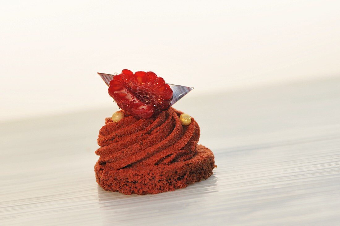 A mini chocolate cake topped with a raspberry