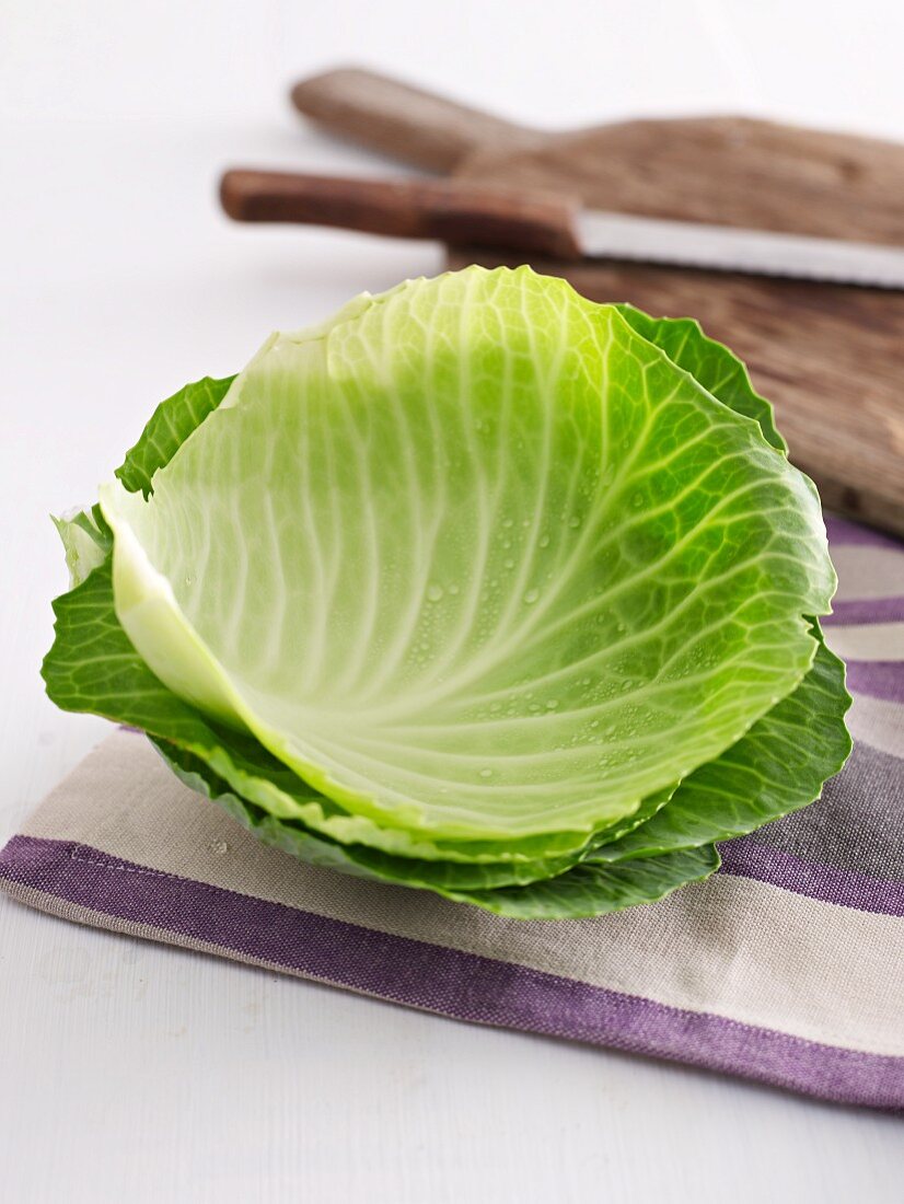 White cabbage leaves and a chopping board in the background