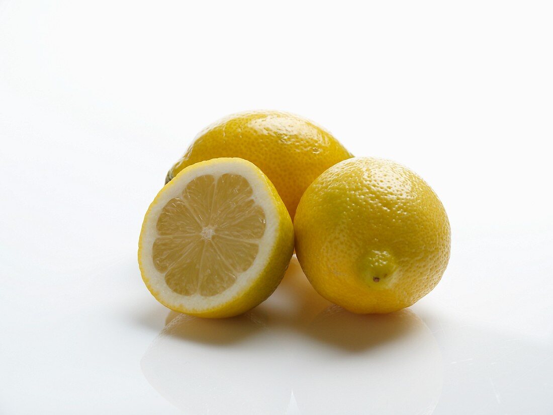 Zwei Zitronen und eine halbe vor weißem Hintergrund