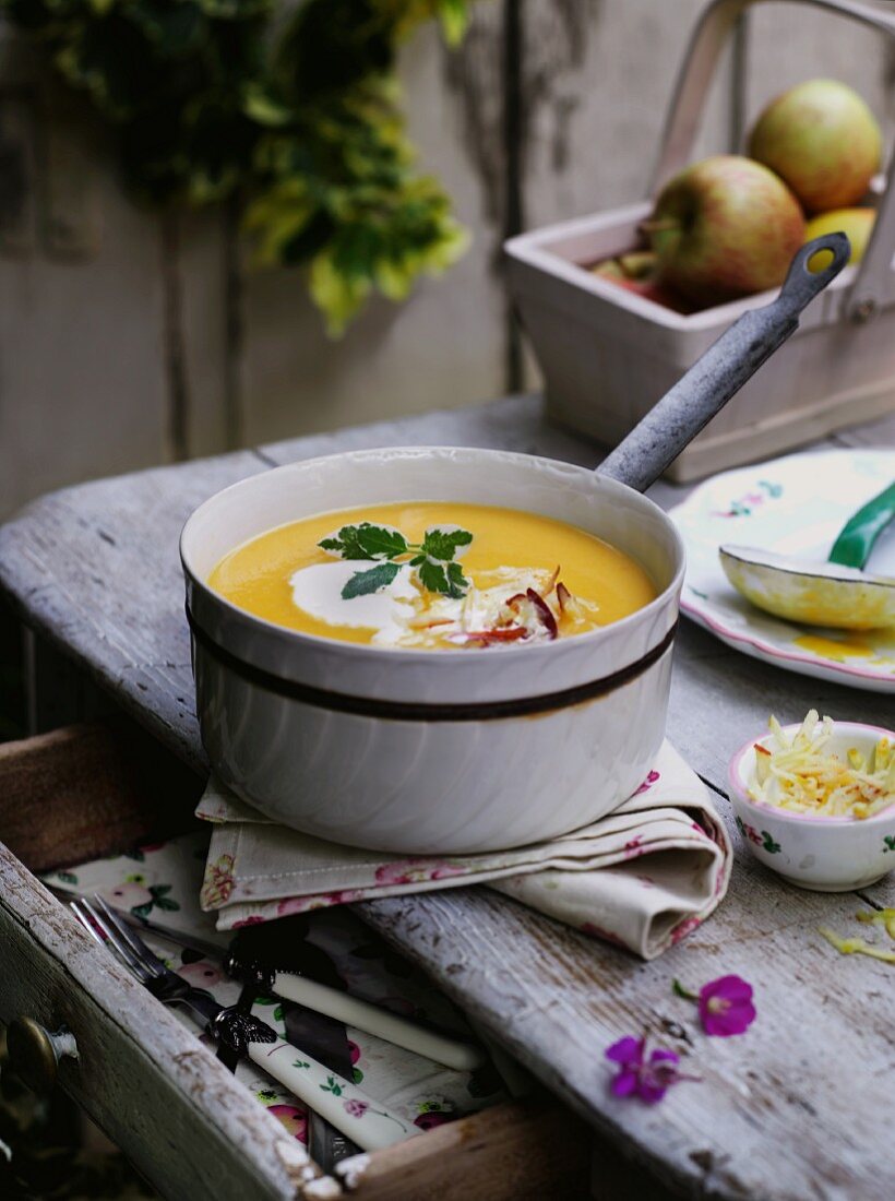 Pumpkin soup in a pot on a rustic table