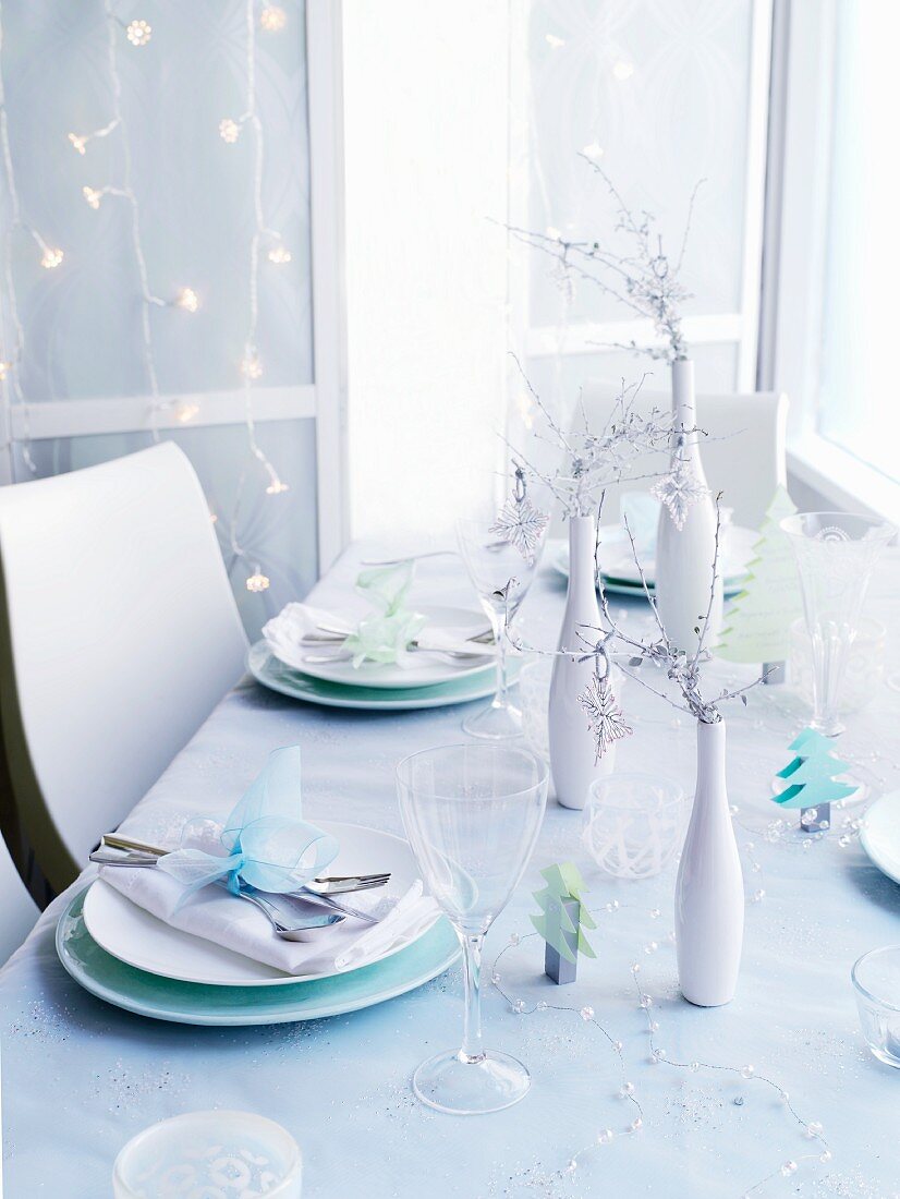 Weihnachtlich gedeckter Tisch vor Wand mit Lichterkette