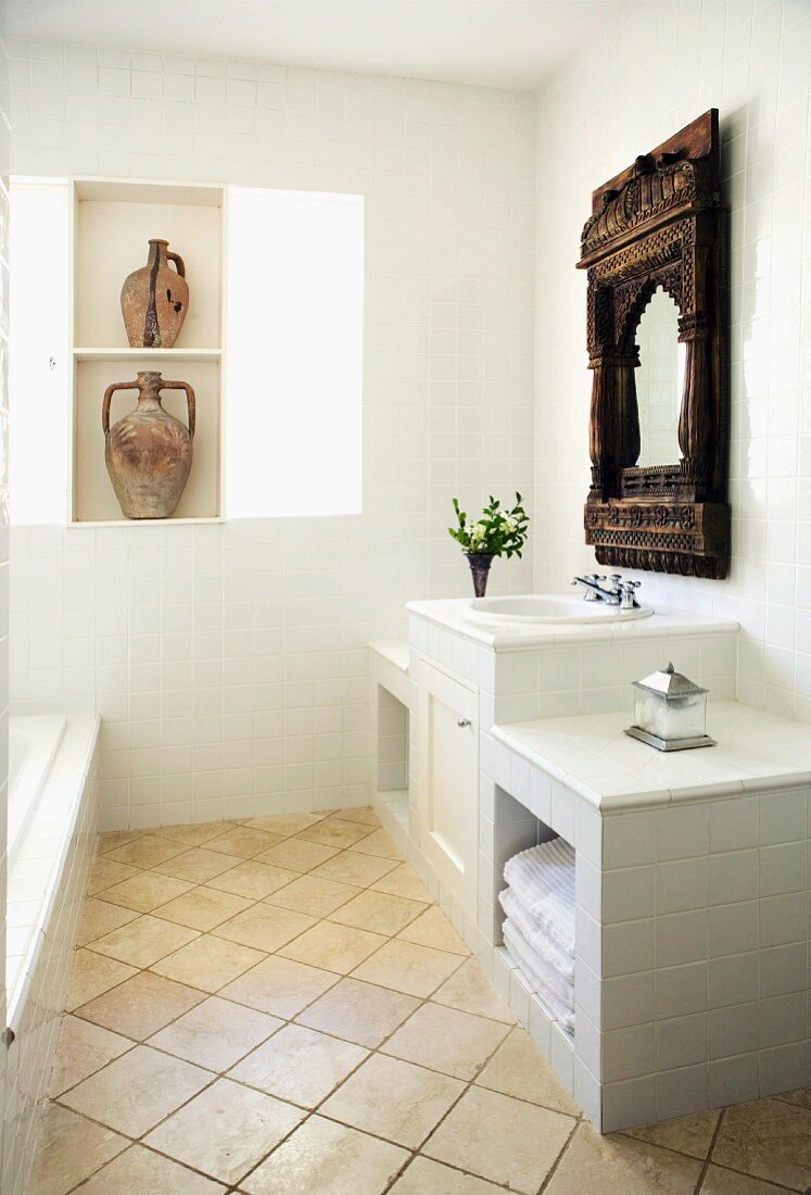 Light and bright bathroom with a white vanity and antique, Indian wall mirror