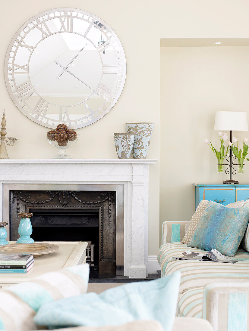 Large clock with mirror face hanging above open fireplace