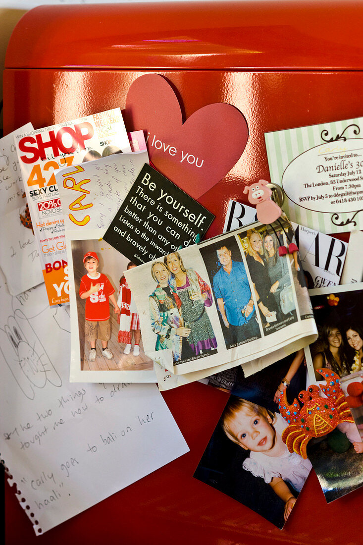 Magnets holding photos to door of red lacquered fridge