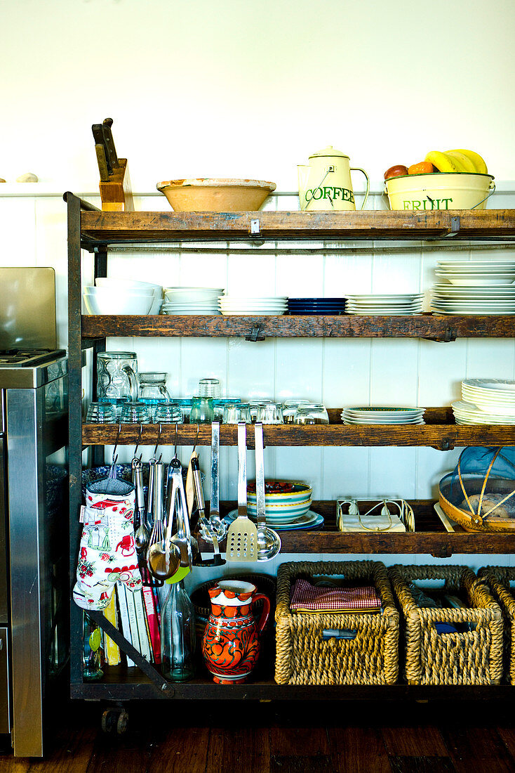 Crockery, baskets and hanging kitchen utensils on vintage wooden shelving