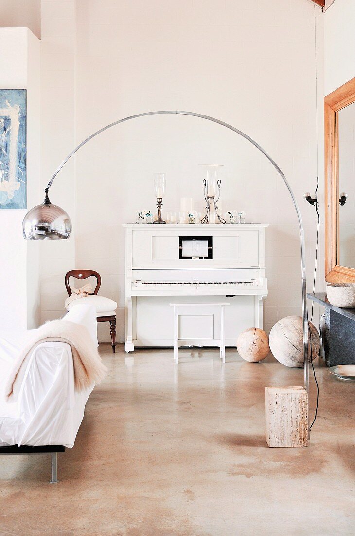 Bauhaus-style arc lamp in front of white antique piano in corner of living room