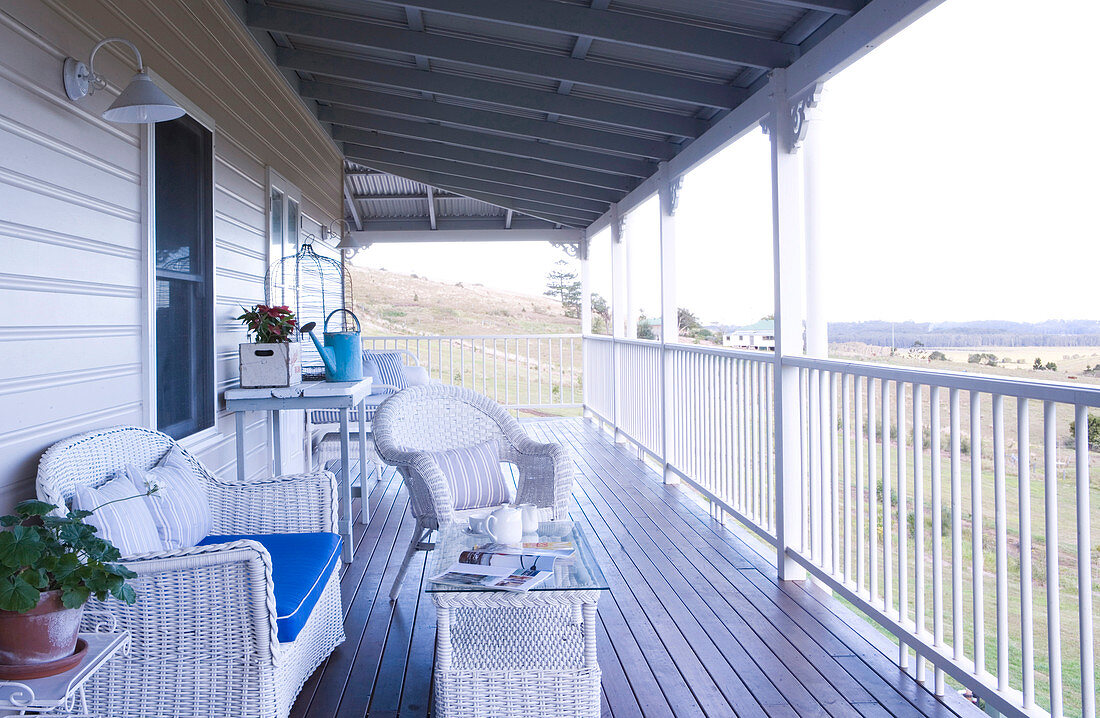 White wicker patio furniture on the veranda of a wooden country home