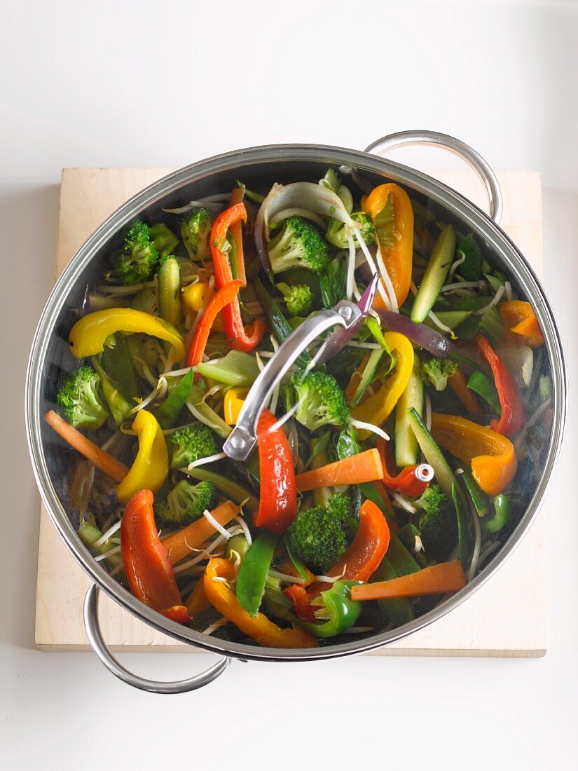 Sautéed vegetables in a pot with a glass lid (seen from above)