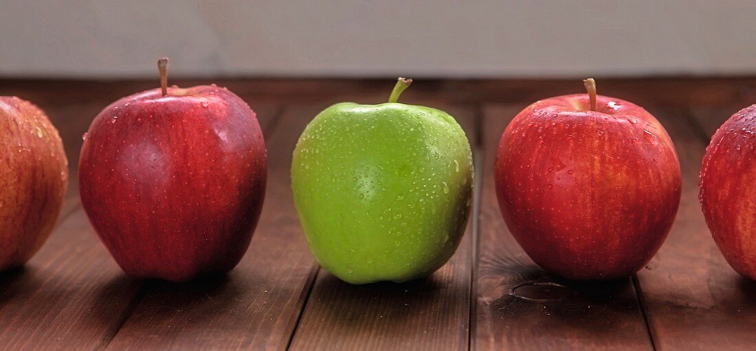 Mehrere rote Äpfel und ein grüner Apfel