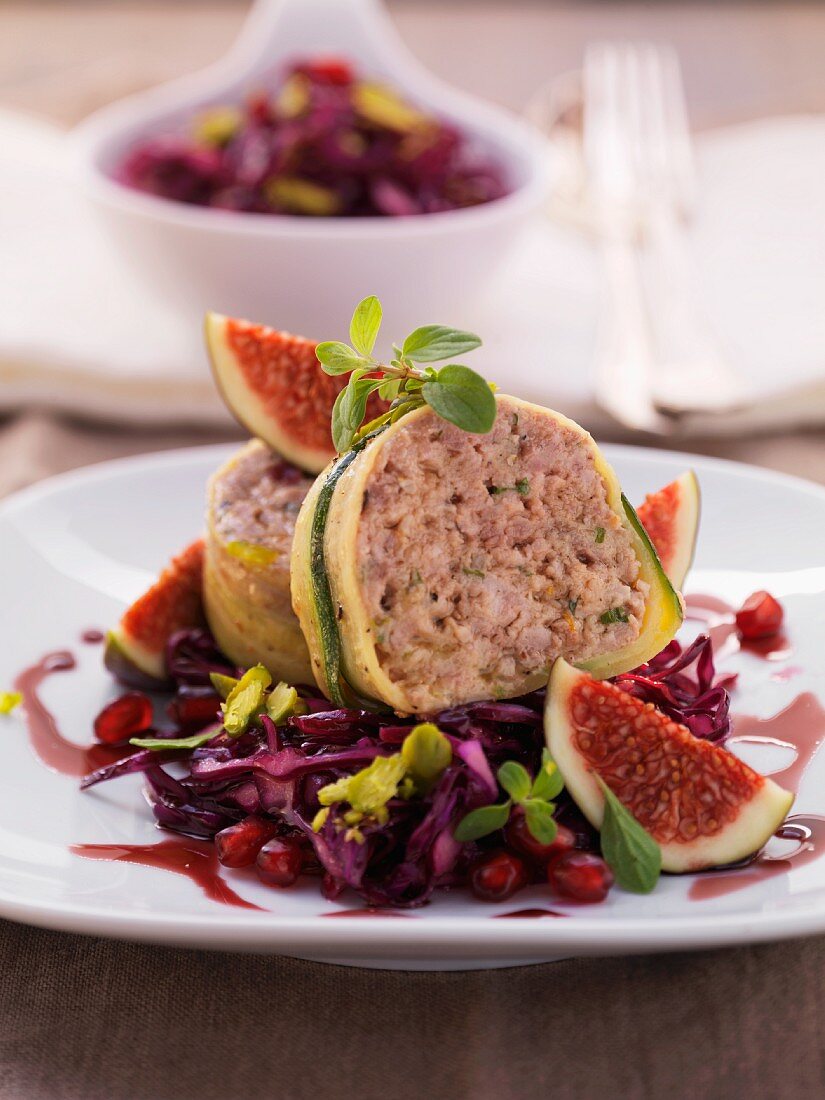 Minced venison meat loaf wrapped in courgettes on a bed of red cabbage