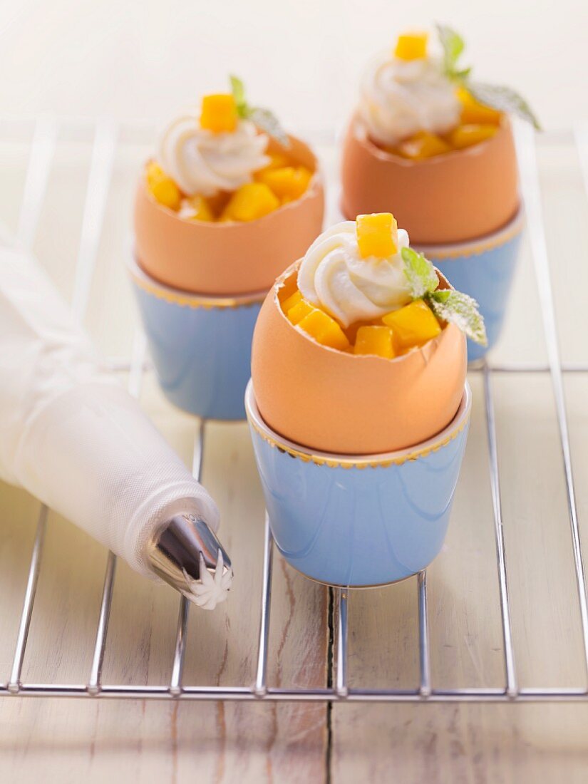 Carrot cakes baked in egg shells and garnished with mango and quark cream