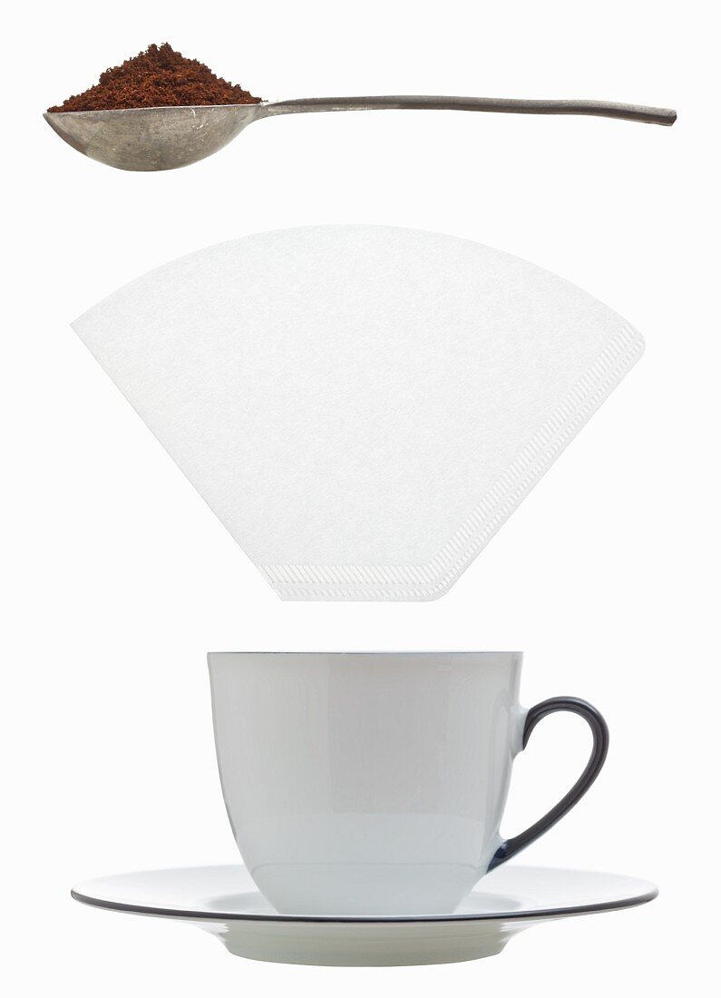 A coffee cup, filter paper and a measuring spoon of ground coffee