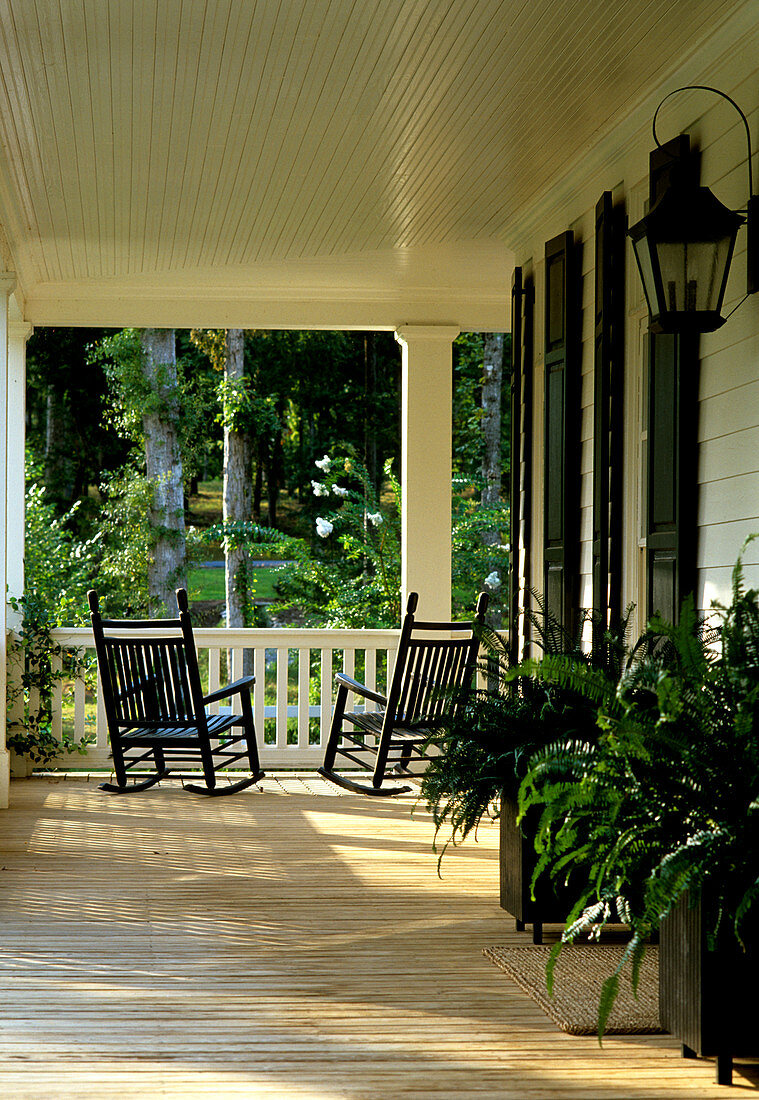 Veranda eines eleganten Landhauses mit Schaukelstühlen aus dunklem Holz